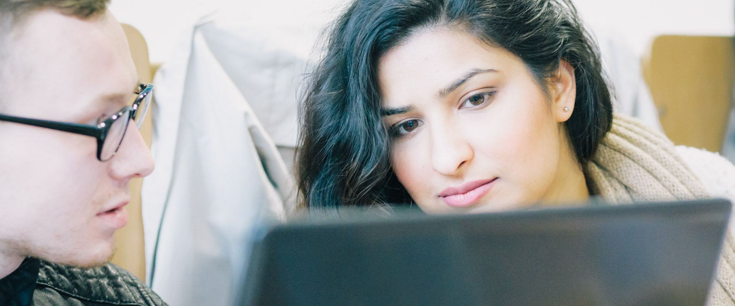 Zwei Personen schauen gemeinsam auf einen Laptop. Two people are looking at a laptop together.