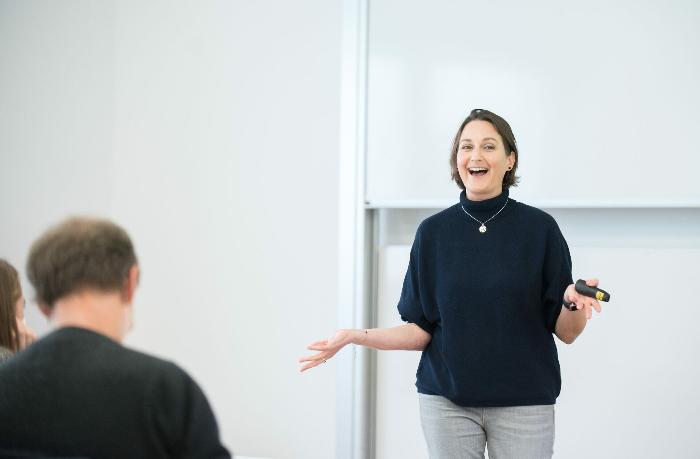 Eine Lehrperson steht vor eine Gruppe Studierender und erklärt etwas.