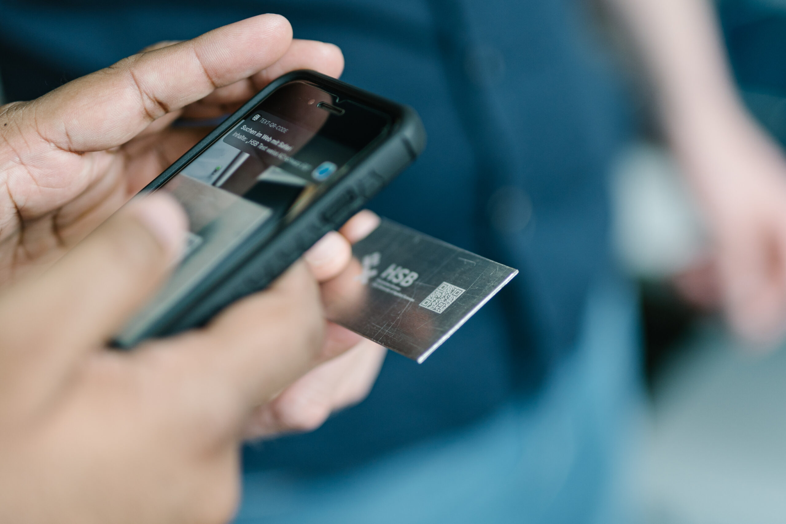 Eine Person hält ein Smartphone in der Hand und scannt einen QR-Code.