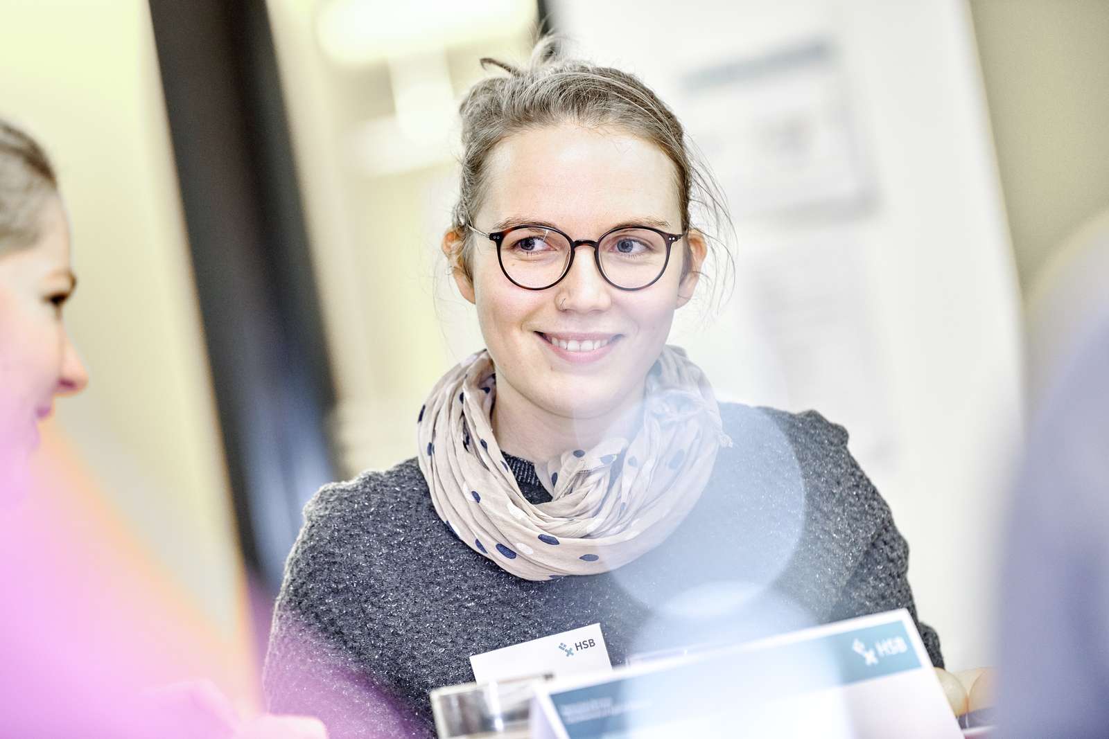 Ein Portrait einer jungen Frau, die in einem Gespräch ist. Vor ihr ist Infomaterial der Hochschule Bremen.