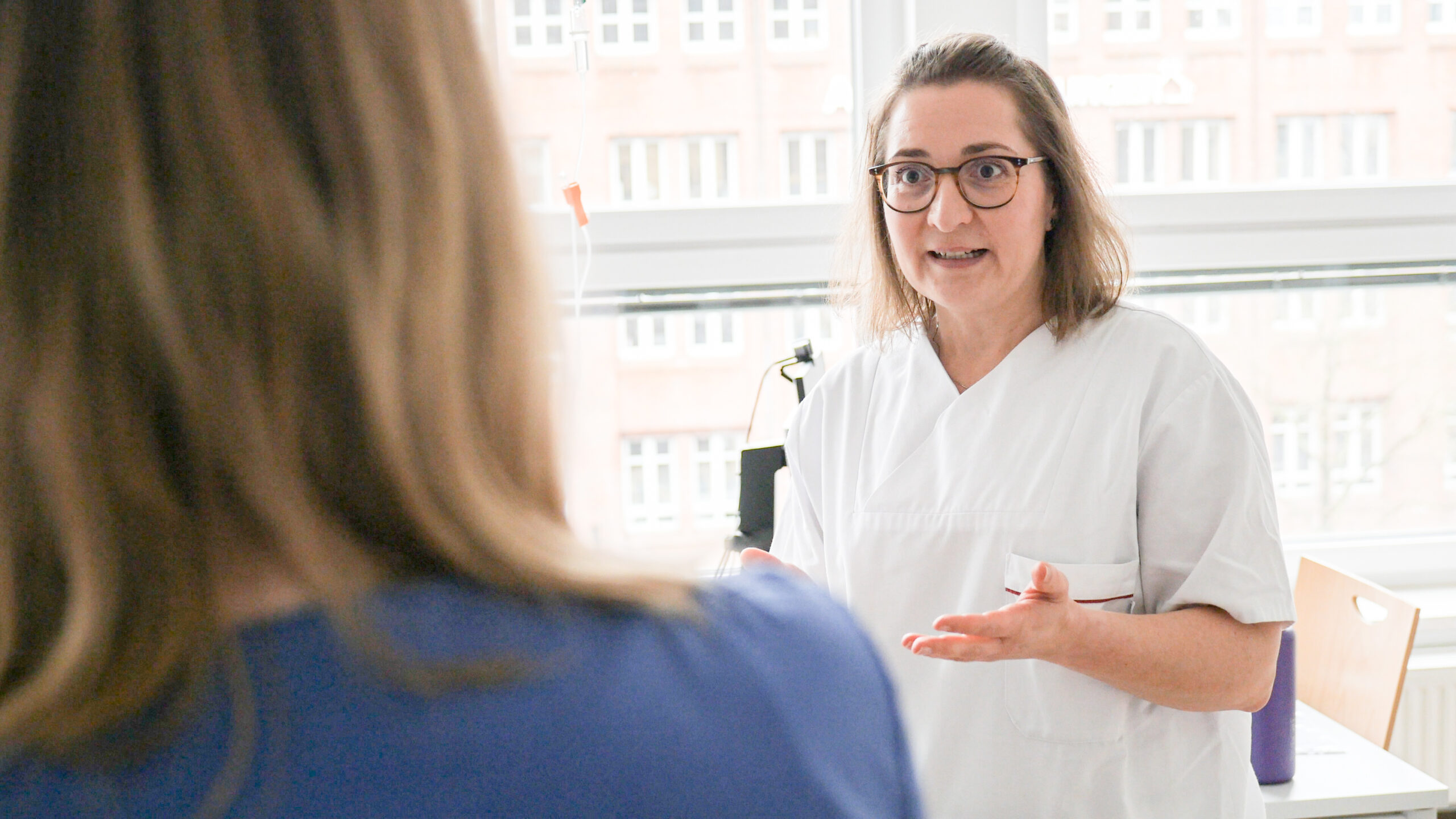 Eine Person in medizinischer Arbeitskleidung erklärt etwas.