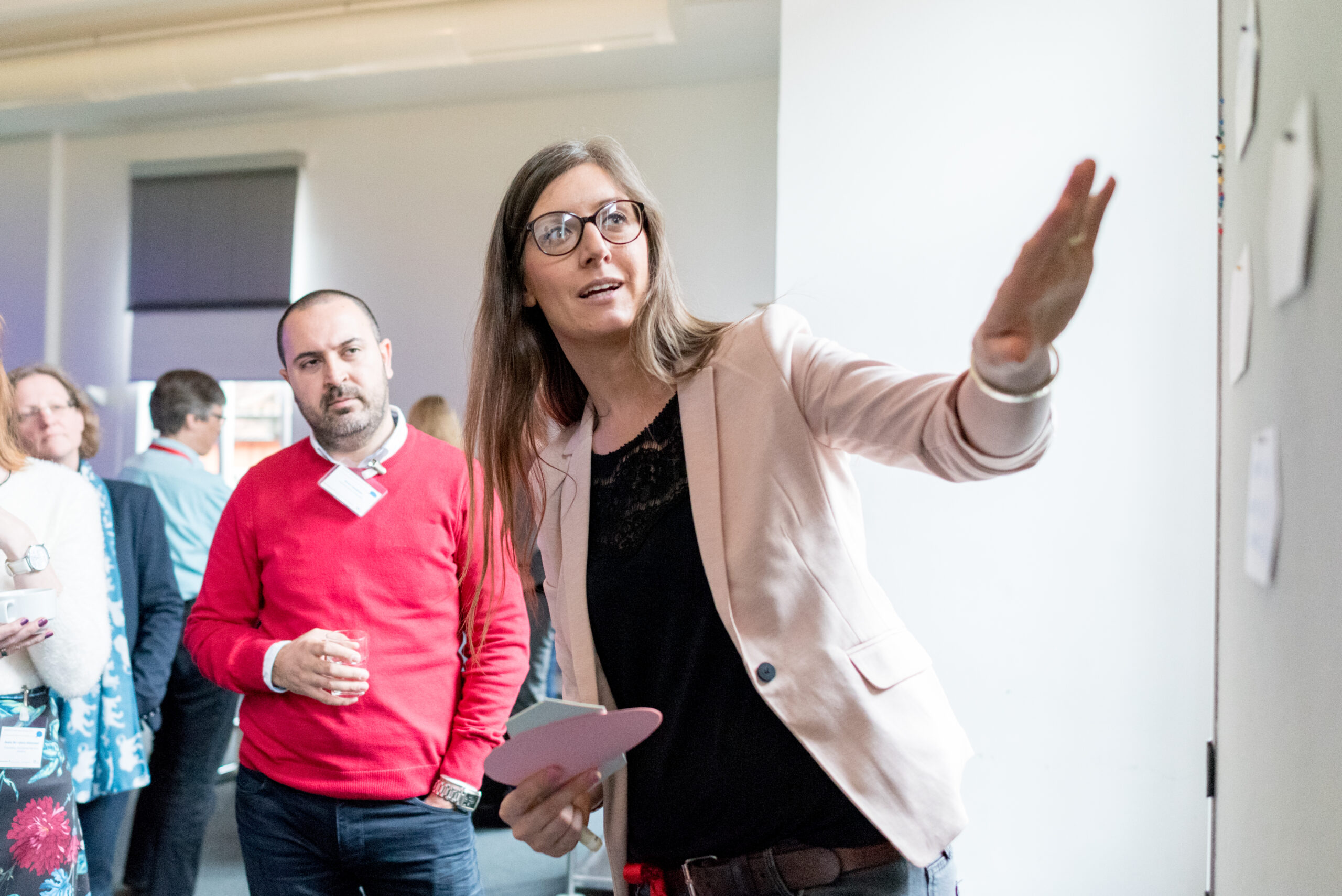 Eine Frau erklärt etwas an einer Pinnwand.