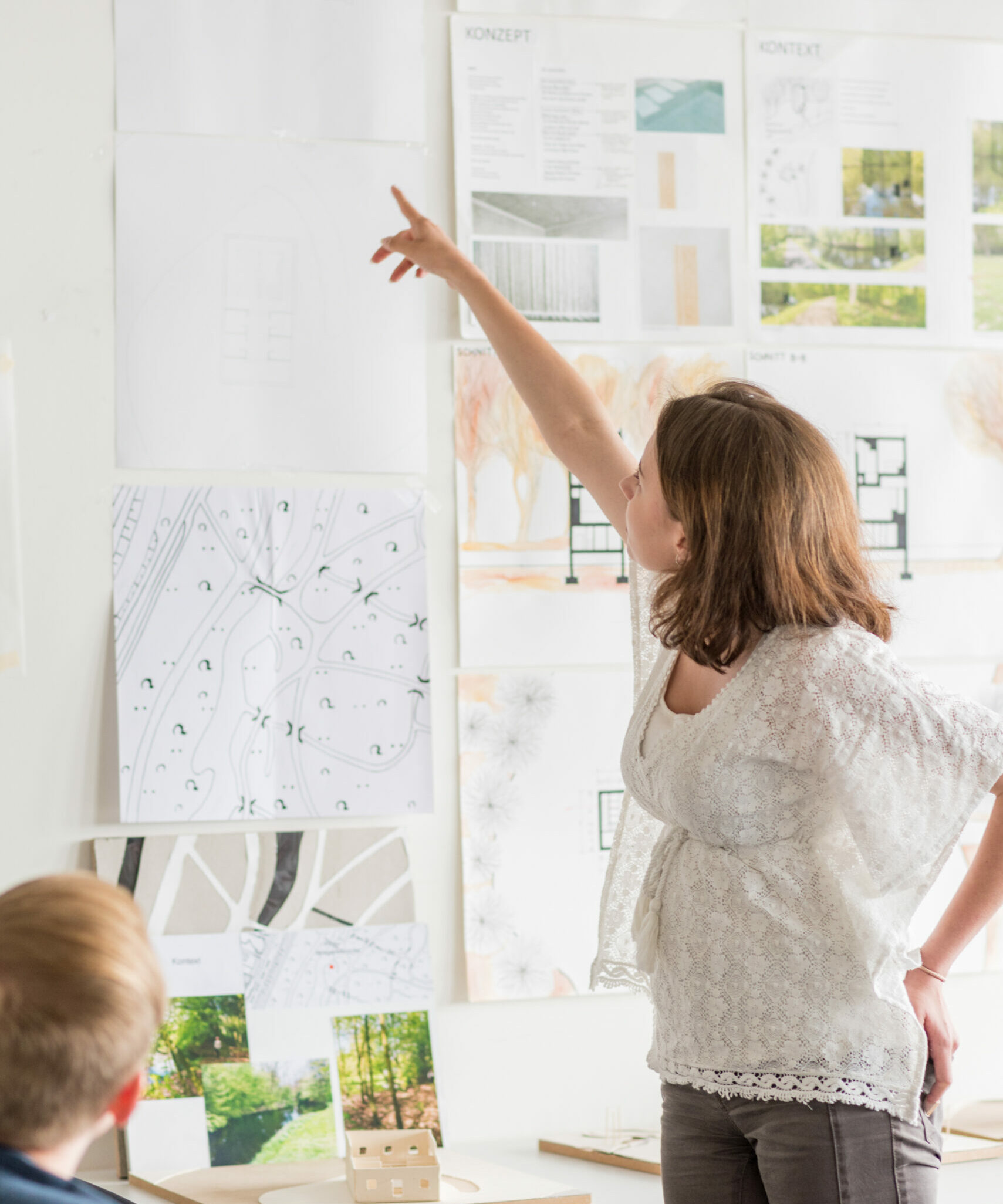 Eine Person zeigt etwas auf einem Architekturkonzept.