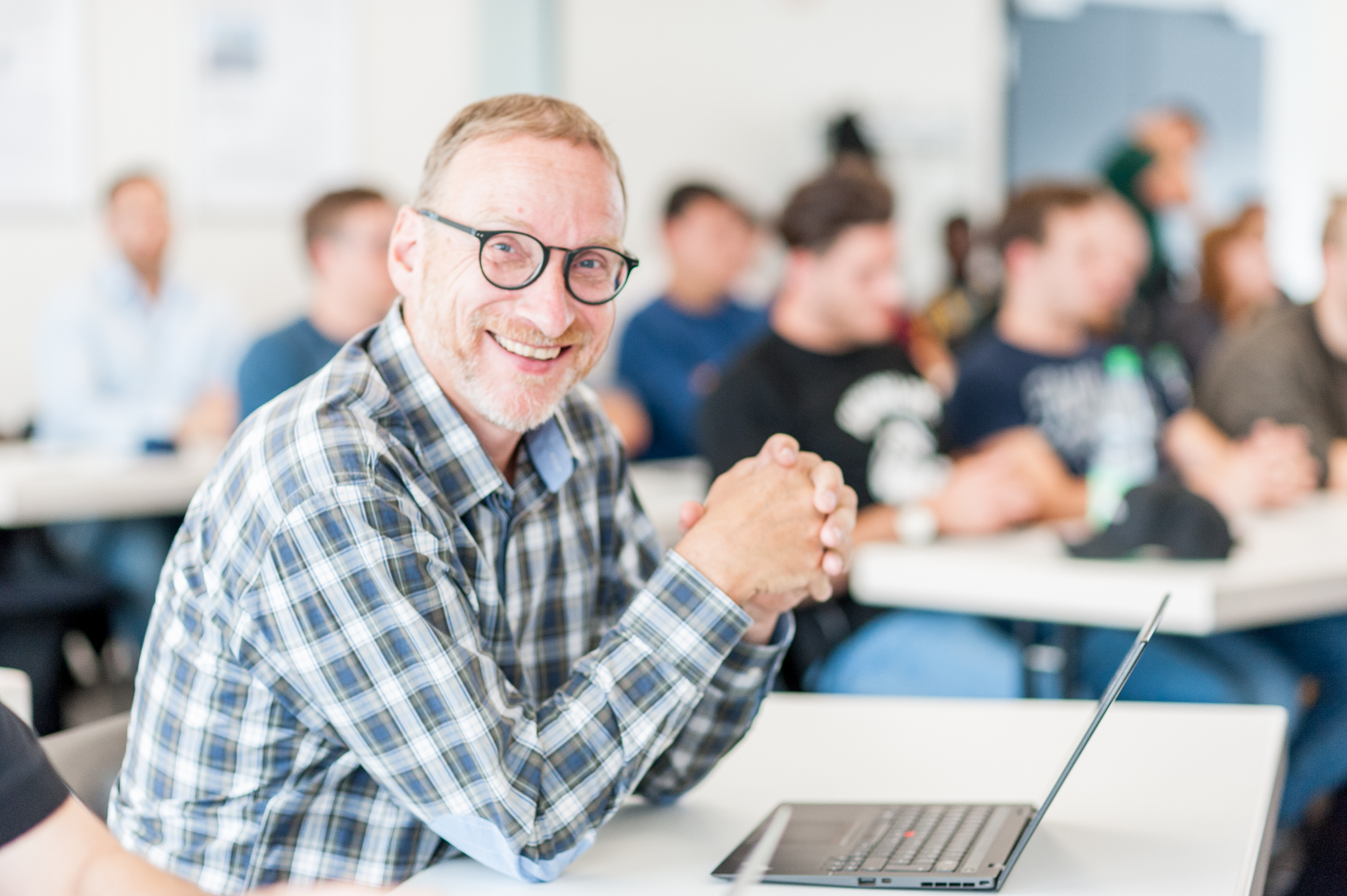 Eine Person im Portrait in einem vollen Vorlesungsraum.
